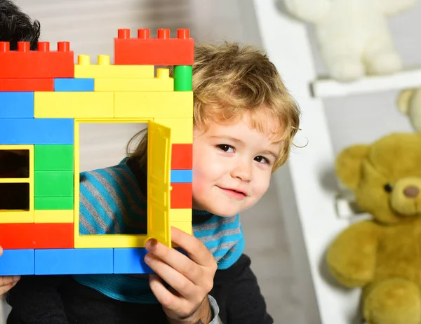 Хлопчик грає з іграшками на фоні дитячої кімнати . — стокове фото