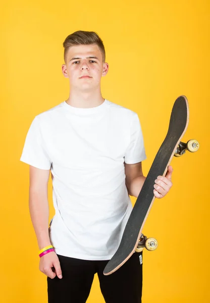 スケートボードを持つ10代の少年。ヒップスター10代の男の子はペニーボードを保持します。ペニースケートボードを持つ都市の少年。子供は趣味に乗ってる。シティスタイルだ。子供はペニーボードに乗ることを学ぶ。トレンディーなティーンスケーター練習 — ストック写真