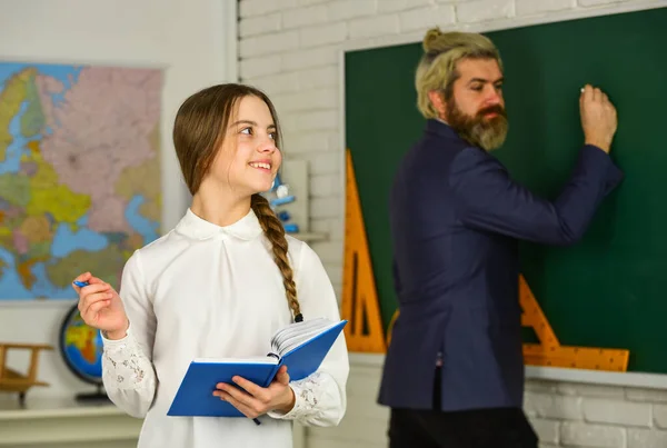 Tieni traccia dei progressi degli studenti. Una ragazzina legge un libro. Esami o lezioni. Torniamo a scuola. Che e 'in servizio oggi. Sviluppo dell'educazione infantile. Studente e insegnante in classe. Scuola ragazza scrittura note — Foto Stock