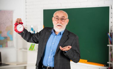 Neden geç kaldın? Kıdemli öğretmen alarm saatini tutuyor. Zaman yönetimi. Ders başlıyor. Sınav şimdi başlıyor. Alarm ver. günaydın. Okula dönelim. Ders çalışma zamanı. disiplin ve dakiklik