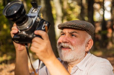 Elle ayarlar. Yaşlı adam doğada ateş eder. Dışarıdaki kameraman. Profesyonel fotoğrafçı. Manzara ve doğa fotoğrafı. Eski fotoğrafçı çekim yapıyor. Emeklilik hobisi. Deneyimli ve kalifiye fotoğrafçı.