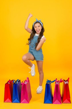 Neşeli kız alışverişin kutlu olsun. Moda dükkanı. Alışveriş paketleriyle küçük bir kız. Çantası olan mutlu bir çocuk. Yaz tarzında küçük bir çocuk. Mevsimlik satışlar. Yaz indirimi. Alışveriş günü. Moda butiği.