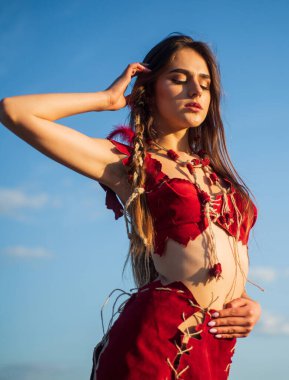 Kabile kıyafetleri. Kabile kültürü. Köklerine geri dön. Ezoterizm ve okültizm. Vahşi ve tehlikeli. Ruhsal gelişim. Deri elbiseli bir kadın gökyüzü arka planı. Etnik kabile kavramı. Seksi kız.