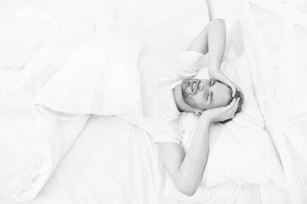 Problemas de sono podem levar a dores de cabeça de manhã. Um homem bonito a relaxar na cama. O ronco pode aumentar as dores de cabeça de risco. Sintoma comum de apneia do sono. Causas da dor de cabeça matinal. Enxaqueca dores de cabeça — Fotografia de Stock