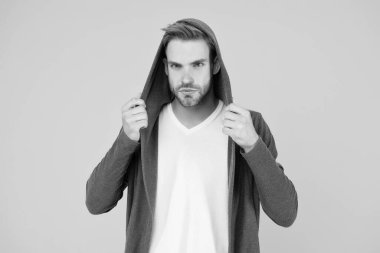 Esneme malzemesi. Yakışıklı adam kapüşonlu şık bir manto giyiyor. Sıradan erkek giyimi. Moda trendleri. Gençler için modern kıyafetler. Günlük yaşam için rahat kıyafetler. Moda adamı sarı arka plan. Moda bakışı.