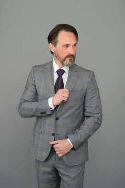 Kazanan bir tavrın var. Resmi tarzda olgun bir adam. İş adamının modaya uygun görünüşü. Ofis tarzı. İş kıyafeti. Moda dolabı. Erkek giyim mağazası. Özel bir kıyafet al. Sakallı adam gri arka plan