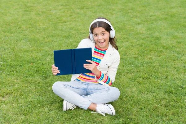 Buď chytrý. Roztomilá holka čte knihu. šťastná školačka s knihou na školním dvoře. Zpátky do školy. Tvrdě pracující dítě ve sluchátkách. koncepce vzdělávání a čtení. rozvoj představivosti — Stock fotografie