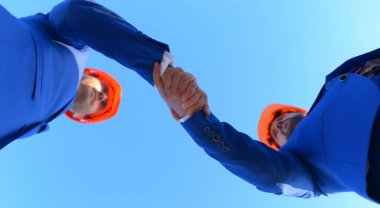 Resmi giyimli ve turuncu kasklı kendine güvenen mimarlar..