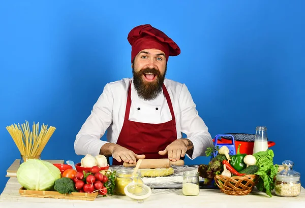 Cook with smile in uniform rolls dough with rolling pin. — Stock Photo, Image