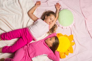 Pembe pijamalı çocuklar yalan söyleyip birbirlerine bakarlar.