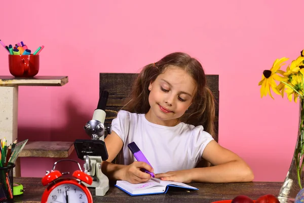 Κορίτσι κάθεται στο γραφείο με πολύχρωμα χαρτικά, ρολόι και μικροσκόπιο — Φωτογραφία Αρχείου