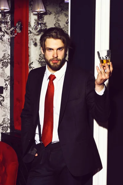 Homme barbu, homme d'affaires en costume, cravate rouge tient verre de whisky — Photo