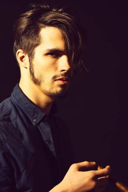 Sigara içen ciddi sakallı bir adam.