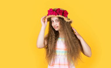 Neşe dolu. çiçek kompozisyonu. Sarı arka planda hasır şapkalı kız. Mutlu çocukluk. Kadın kuaför salonu. Çiçekli güzel kız. Küçük kız pembe çiçekli bir şapka takıyor.