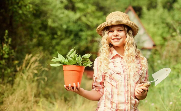 Happy childhood. Child in hat with shoulder blade small shovel hoe. Happy smiling gardener girl. Ranch girl. Planting plants. Little kid hold flower pot. Spring country works. Happy childrens day — Stock Photo, Image