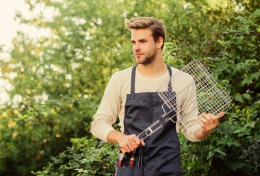 Arka bahçe barbekü partisi. Izgara yapmak için farklı yöntemler. Adam ızgara ızgarasını beklesin. Izgara yemek. Açık havada et kızartmak için aletler. Piknik konsepti. Yemek pişiren yakışıklı adam. Sağlıklı yemek. Tarif ızgarası