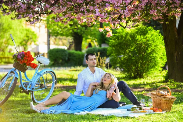 Lovely day. woman and man lying in park and enjoying day together. valentines day picnic. romantic picnic in park. couple date on blanket under sakura flowers. camping. happy couple in love