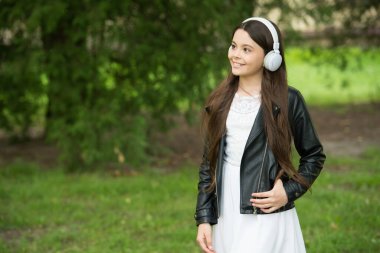 Yaz mevsimi geldi çattı. Mutlu kız yaz parkında müzik dinler. Yeni teknoloji. Modern hayat. Dinle ve keyfini çıkar. Sakin ol ve müzik dinle.