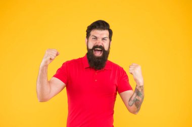 İç enerji. Başarı için motive. Mutlu adam sarı arka planda başarı jesti gösteriyor. Zafer ve başarı. Sıradan giyinmiş sakallı adam kutlama yapıyor. Mutluluk ve neşe. Kazanan ve kazanan. Neşeli adam.