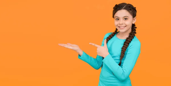 Stylische Zöpfe und Zöpfe. Kopierraum. Teenager Mädchen präsentiert Produkt. professionelle Frisur. Kindermode und Schönheit. Kleines Mädchen nach Friseur. Kinderglück. schöne geflochtene lange Haare — Stockfoto