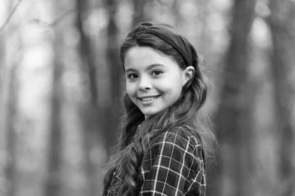 Menina sorridente usar fita de cabeça atada. Tendências de acessórios de cabelo maiores. Adorável menina xadrez camisa desgaste cabeça vermelha. Tendência moda. Acessórios. Fantasia criança natureza fundo. Cabeça acolchoada — Fotografia de Stock