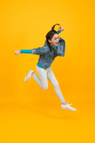 Voar tão alto. O miúdo está a divertir-se. sucesso no esporte. criança vencedora feliz. adolescente salto menina no fundo amarelo. Isto é um triunfo total. correr para o sucesso. conceito de felicidade infantil — Fotografia de Stock