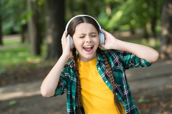 Everything but music. Happy girl sing to music summer outdoors. Little child wear headphones playing music. Modern life. New technology. Summer holidays. Leisure and pleasure. Give in to the groove