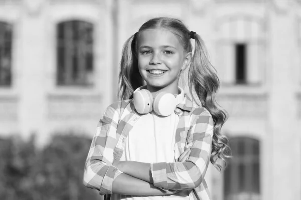 Positive hipster kid in earpieces. little girl smiling in sunshine. good mood any weather. spring or summer vacation. free time with favorite music. digital device for advanced children — Stock Photo, Image