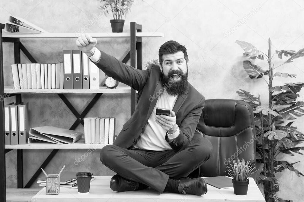 Play game. Good news. Social networks. Online relax. Self care. Relaxation techniques. Mental wellbeing and relax. Man bearded manager formal suit sit lotus pose relaxing. Application smartphone