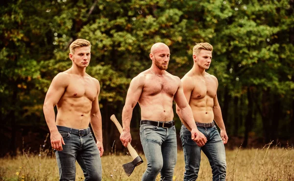 Best exercise. brutal and strong male. sexy guys six packs and biceps. protein or steroids. bodybuilding concept. relax after work in the forest. three muscular men with axe. athletic man use ax — Stock Photo, Image