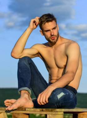 Fitness modeli. Atletik yakışıklı maço kot pantolon giyiyor. Kaslı vücut. Yaz gezileri kitabı. Kaslı, çıplak gövde. Altı paket kaslı göğüs. Açık havada mavi gökyüzü arka planı. Erkek güzellik konsepti