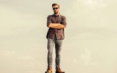 Göz sağlığı. Yakışıklı adam güneş gözlüğü takıyor. Moda güneş gözlüklü hippi. Modaya uygun güneş gözlükleri. Ultraviyole koruma kavramı. Erkek gözlüklü model açık havada mavi gökyüzü arka planı. Mükemmel görüş