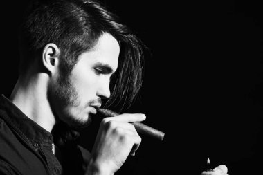 Ciddi sakallı adam puro içiyor.