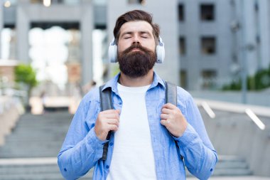 Modern hayat. Şehir merkezinde yürüyen kulaklıklı bir adam. Müzik dinliyordum. Sırt çantası olan yakışıklı bir hippi. İyi ses. İşe günlük rota. Boş sokaklarda yürüyorum. Müzikle baş başa