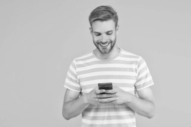 SMS mesajı gönderiliyor. Mutlu adam SMS 'i akıllı telefon sarı arka planıyla gönderiyor. SMS mesajı. Kısa mesaj servisi. Yeni teknoloji. Taşınabilir yaşam tarzı. Modern hayat. Güvenilir SMS teslimatı