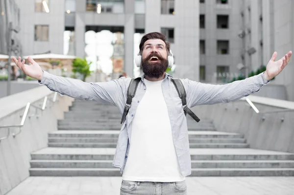 Concepto energético. Alegría y positividad. La vida moderna. Hombre con auriculares caminando por el centro de la ciudad. Escuchando música. Guapo hipster con mochila. Buen sonido. Ruta al trabajo. Sola con música. Libre y feliz — Foto de Stock