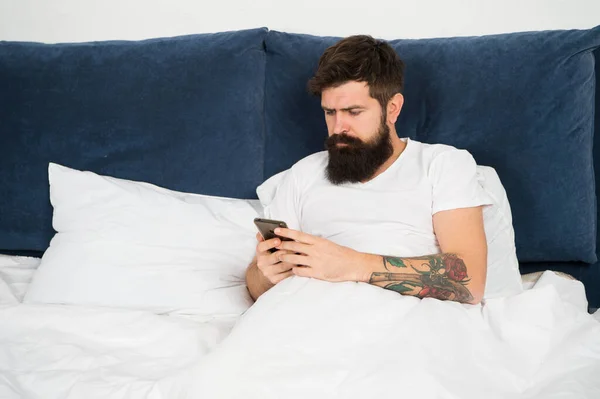 Először is. Szakállas férfi sms-t ír az ágyban. Hipster üzenetet küld okostelefonnal. Mobil üzenet. Rövid üzenet szolgáltatás. Mobil életmód. Közösségi oldalak. Alkalmazás letöltése. Ellenőrizze e-mail — Stock Fotó