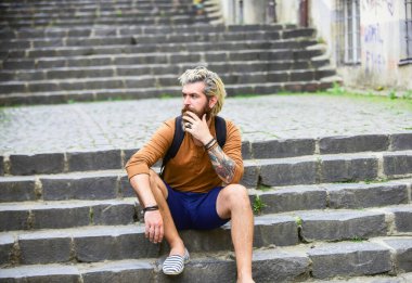 Gizli turistik mücevher. Arka sokakları araştırın. Sakallı hippi dışarıda rahatla. Erkek turist merdivenlerde oturur. Sakallı ve bıyıklı adam şehir alanını rahatlatıyor. Turizm konsepti. Yeraltı kültürü