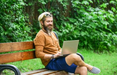 Temiz hava. Gezici internet. İstediğin yerde çalışabilirsin. Çevik iş. Sakallı adam park doğasında bankta oturuyor. Çalış ve rahatla. İnternetten alışveriş. İnternette çalışıyorum. Hipster parkta çalışmaktan esinlendi
