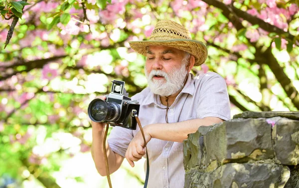 Retirement travel. Capturing beauty. Happy grandfather. Spring holidays. Travel photo. Photographer in blooming garden. Senior man hold professional camera. Photography courses. Travel and tourism