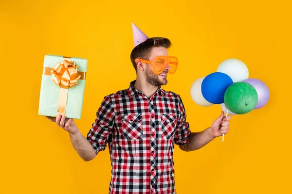 Een echte winkelverslaafde. Hij heeft feestelijke ballonnen. Fijne feestdag. Tijd voor plezier en cadeautjes. Gelukkige verjaardag of trouwdag. voel vrolijkheid en vreugde. Puur feestganger. grappige man met verjaardagskapje — Stockfoto