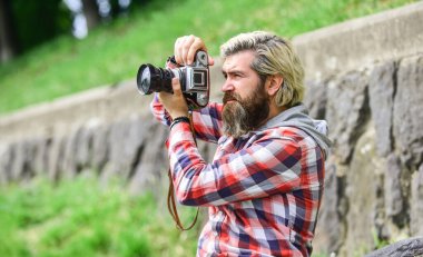 İçerik yaratan. Şaheser fotoğrafı. Sakallı bir adam fotoğraf çekiyor. Fotoğrafçı konsepti. Sakallı hippi fotoğrafçı klasik kamera tutuyor. Fotoğrafçı amatör fotoğrafçı doğa geçmişi