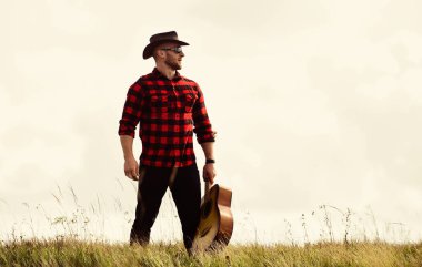 Tek kelimeyle zarifti. Hipster modası. Mutlu ve özgür. Batı kampı ve yürüyüş. Akustik gitaristli kovboy adam. Kareli gömlekli, gitarlı seksi bir adam. country müzik şarkısı