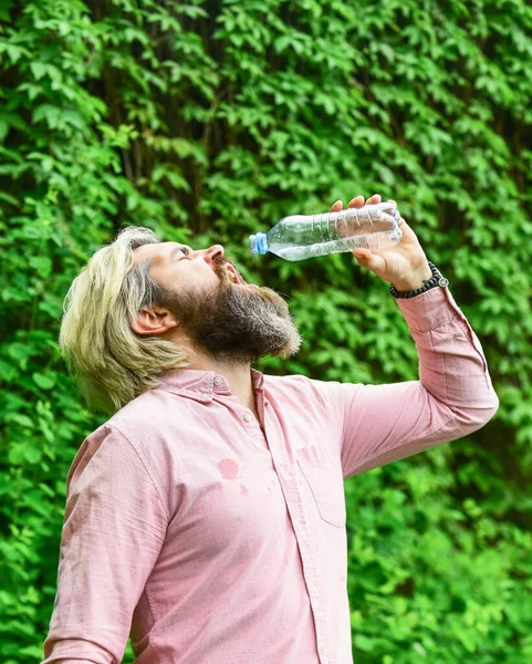 Törstig kille som dricker vatten på flaska. En hälsosam livsstil. Varmt väder. Uppfriskande lemonad. Sommarvärme. Läskvatten. Vattenbalans. Man skäggig turist dricksvatten plastflaska natur bakgrund — Stockfoto