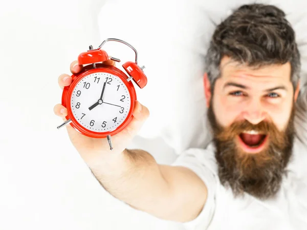 Man with yawning happy face lies on pillow, holds clock. — Stock Photo, Image