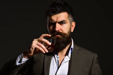 Ciddi yüzlü bir adam bir bardak alkolle kadeh kaldırıyor.