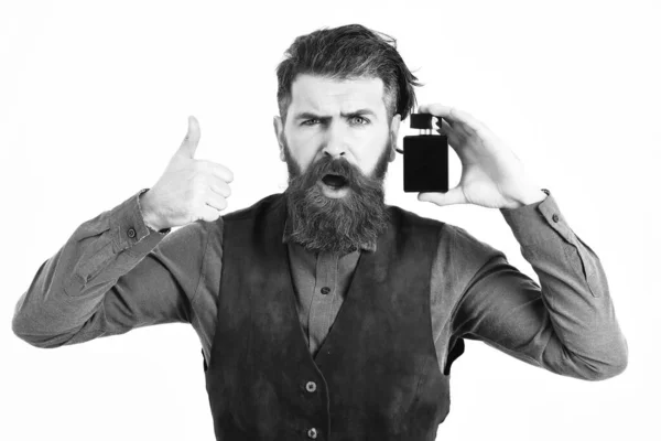 Hombre barbudo sosteniendo perfume con la cara sorprendida — Foto de Stock