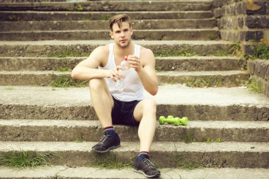 Ciddi yüzlü sporcu beton merdivenlerde oturuyor.