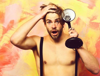 Pantolon giymiş, elinde lamba tutan beyaz sakallı, maço bir adam.