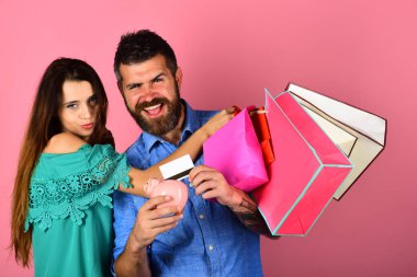 Birbirini seven çiftler alışveriş torbalarını pembe arka planda tutarlar..